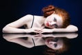 Young woman with ginger hair over reflection mirror on blue back Royalty Free Stock Photo