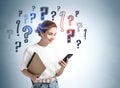 Young woman girl in casual clothes with phone and notes over grey wall with question marks Royalty Free Stock Photo