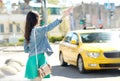 Young woman or girl catching taxi on city street