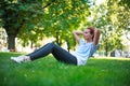 Young woman in city park on green grass doing stretching fitness exercises outdoors Royalty Free Stock Photo