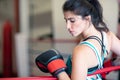 A young woman girl is hanging on the ropes of a boxing ring, resting, wearing boxing gloves. Royalty Free Stock Photo