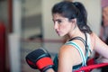 A young woman girl is hanging on the ropes of a boxing ring, resting, wearing boxing gloves. Royalty Free Stock Photo