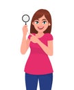 Young woman or girl holding a magnifying glass and pointing index finger. Person showing magnifier lens in hand. Female character. Royalty Free Stock Photo