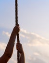 Young woman or girl holds hands on rope and climbs up in physical education class