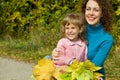 Young woman and girl laugh with leaves in garden