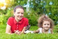 Young woman and girl lying on the grass, looking at the camera. family leisure in nature together. happy mother and daughter playi Royalty Free Stock Photo