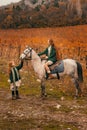 A young woman and a girl with red long hair walk in the wineries in the fall and ride horses