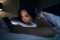 Young woman or girl using smartphone app social media while lying in bed at night Royalty Free Stock Photo