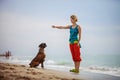 Young woman giving commands to boxer dog while walking