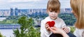 Young woman is giving a knitted heart to a small child