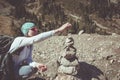 A young woman in glasses builds a pyramid of stones. Stones in the background of trees