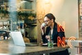 Young woman in glasses with coffee looking away and thinking. Business woman having a coffee and looking out of the window