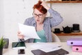 Young woman with glasses with red short hair is shocked by what she sees in the official documents