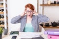 Young woman with glasses in shock holds her head with her hands over a stack of documents lying on the desk Royalty Free Stock Photo