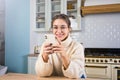 Young woman in glasses talking via mobile phone while resting in home