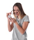 Young woman with glasses using mobile phone on white. Vision problem