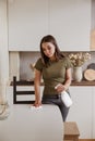 Young woman without gloves cleaning table with spray rag in kitchen Royalty Free Stock Photo