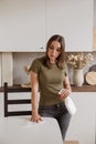 Young woman without gloves cleaning table with spray rag in kitchen Royalty Free Stock Photo