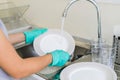 Young woman with gloves washing dishes Royalty Free Stock Photo