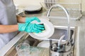 Young woman with gloves washing dishes