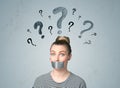 Young woman with glued mouth and question mark symbols Royalty Free Stock Photo