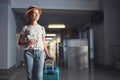 Young woman goes at airport at window with suitcase waiting for