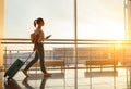 Young woman goes at airport at window with suitcase waiting for Royalty Free Stock Photo