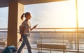 Young woman goes at airport at window with suitcase waiting for