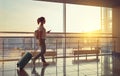 Young woman goes at airport at window with suitcase waiting for Royalty Free Stock Photo