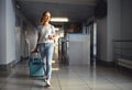 Young woman goes at airport at window with suitcase waiting for