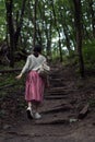 Young woman goes on a forest path. The girl herself walks in the woods. Wild park. Back view