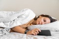 Young woman goes to sleep Phone addiction, insomnia. try to fall asleep. Sleep tracking on the phone. Circadian rhythm.