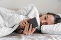 Young woman goes to sleep Phone addiction, insomnia. try to fall asleep. Sleep tracking on the phone. Circadian rhythm.