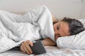 Young woman goes to sleep Phone addiction, insomnia. try to fall asleep. Sleep tracking on the phone. Circadian rhythm.