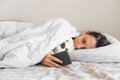 Young woman goes to sleep Phone addiction, insomnia. try to fall asleep. Sleep tracking on the phone. Circadian rhythm.