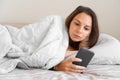 Young woman goes to sleep Phone addiction, insomnia. try to fall asleep. Sleep tracking on the phone. Circadian rhythm.