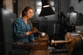 A young woman in goggles and overalls is standing near the lathe. Profession concept Turner, Metalworking, Turning