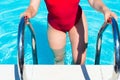 Young woman going out of swimming pool via a ladder Royalty Free Stock Photo