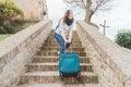 Young woman is going upstairs with her heavy luggage