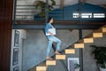 Young woman going upstairs, holding laptop under arm