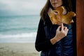 Young Woman with Gold Autumn leaf against the sea in rainy day Royalty Free Stock Photo