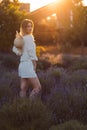 A Young Woman at the Golden Hour Stands in a Lavender Field in White Cotton Suit