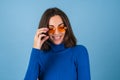 Young woman in golf on a blue background in stylish bright orange glasses