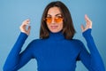 Young woman in golf on a blue background in stylish bright orange glasses