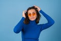 Young woman in golf on a blue background in stylish bright orange glasses