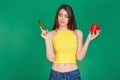 Young woman in good shape holding green cucumber and red salad pepper in hands and thinking about choice.Healthy food Lifestyle Di Royalty Free Stock Photo