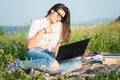 Young woman on grass with open laptop