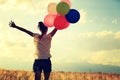 Young woman on grassland with colored balloons