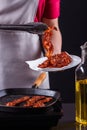 Young woman in a gray apron fries bacon Royalty Free Stock Photo