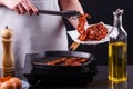 Young woman in a gray apron fries bacon Royalty Free Stock Photo